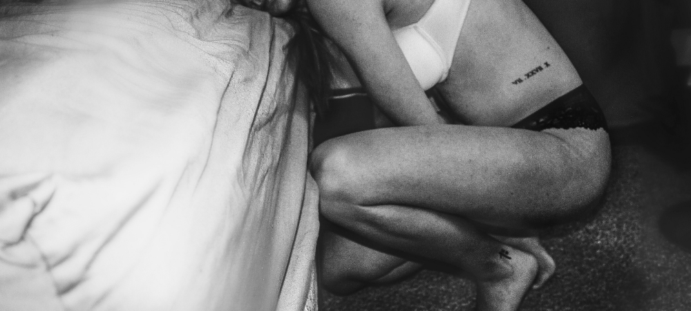 Woman knelt by her bed in discomfort